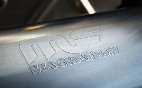 Close-up of the MagnaFlow logo embossed on the stainless steel body of the MagnaFlow Muffler Mag SS 14X4X9 2.5 D/D.
