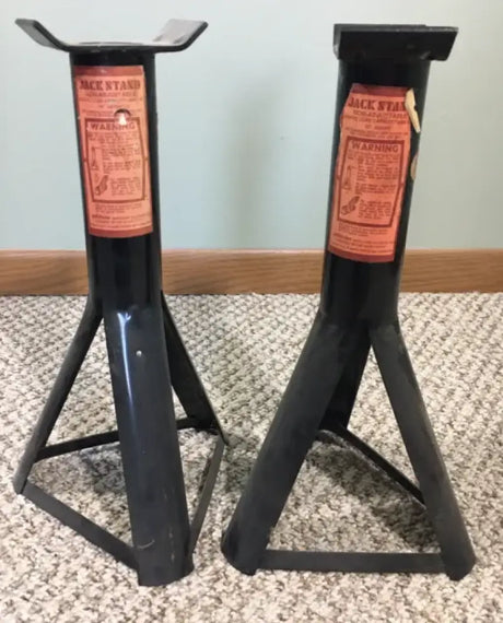 Two black jack stands with orange warning labels.