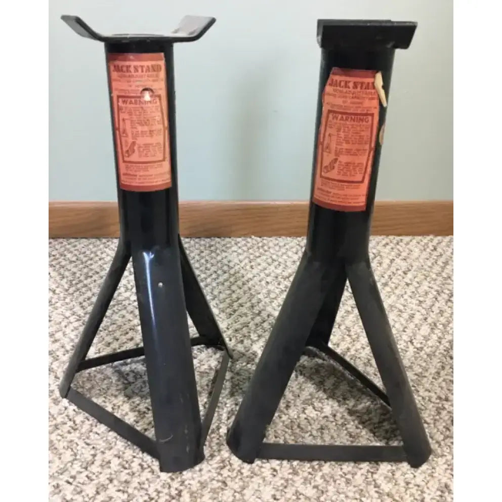 Two black jack stands with orange warning labels.
