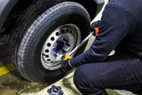 Mechanic tightening Mishimoto locking lug nuts on a car tire for secure fit