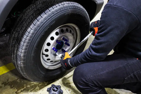Mechanic tightening Mishimoto locking lug nuts on a car tire for secure fit