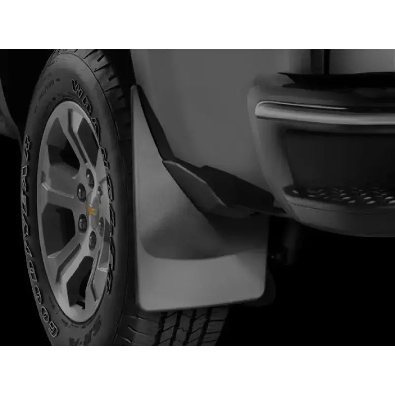 Black thermoplastic direct-fit contoured mud flap set of 2 without logo featuring QuickTurn fastening system, mounted on the rear fender of a vehicle.