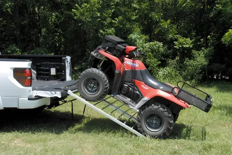 QuadBoss Bifold Ramp 50x72 - 560052 in use, facilitating easy ATV loading onto a white truck in an outdoor setting. Durable, compact, and reliable ramp for effortless equipment and vehicle transport.