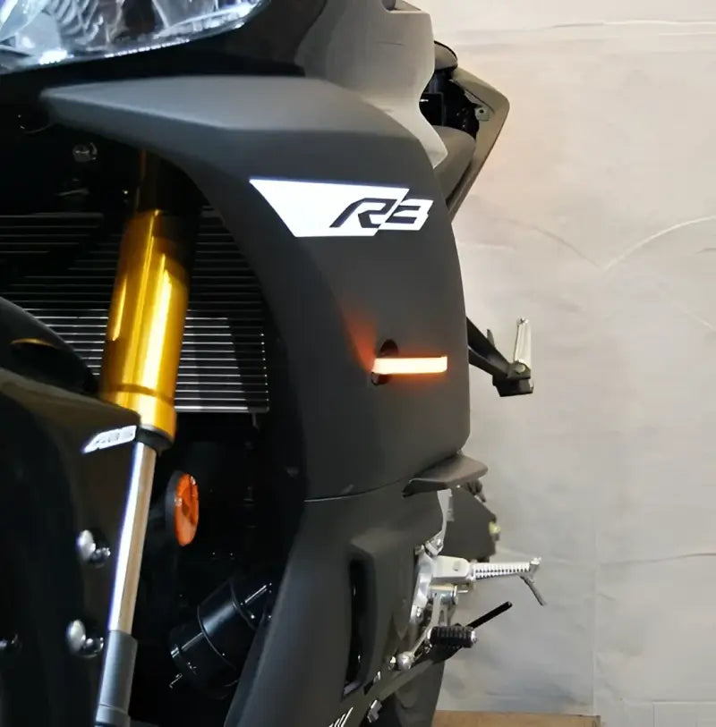Front LED turn signals for Yamaha R3 motorcycle, sleek design with illuminated amber lights.