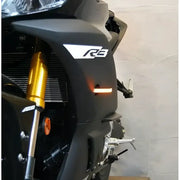 Front LED turn signals for Yamaha R3 motorcycle, sleek design with illuminated amber lights.
