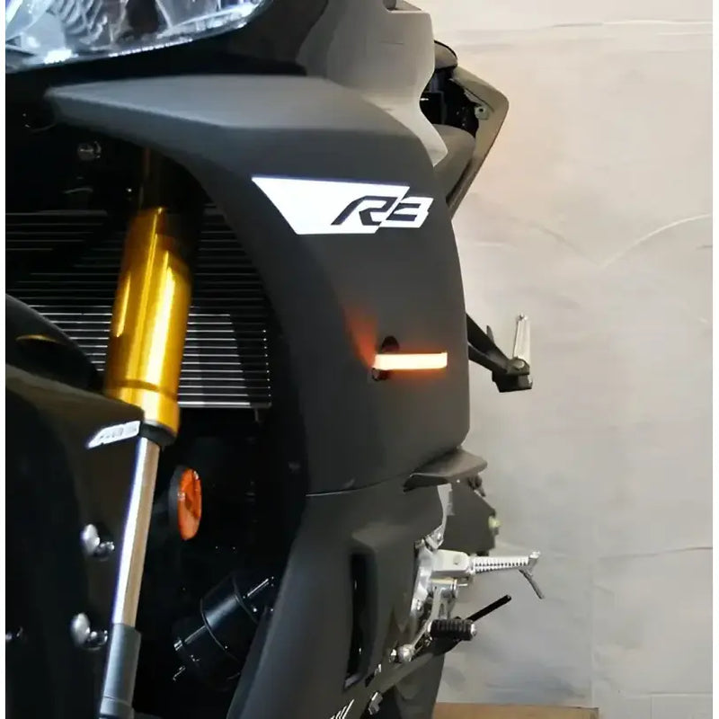 Front LED turn signals for Yamaha R3 motorcycle, sleek design with illuminated amber lights.