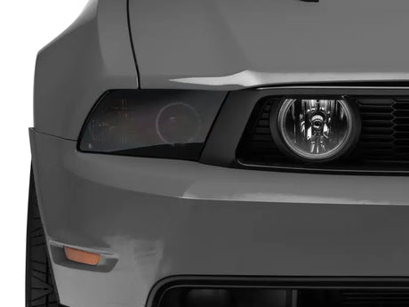 Gray car front with tinted headlight showcasing Raxiom LED Halo Fog Lights for Mustang