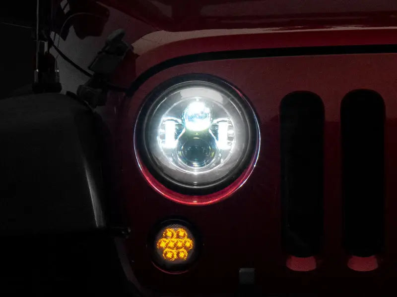 Illuminated Jeep headlight showing LED Daymaker headlights in chrome housing