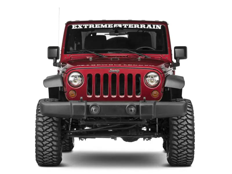 Red Jeep Wrangler with off-road tires showcasing Raxiom LED Daymaker headlights in chrome housing