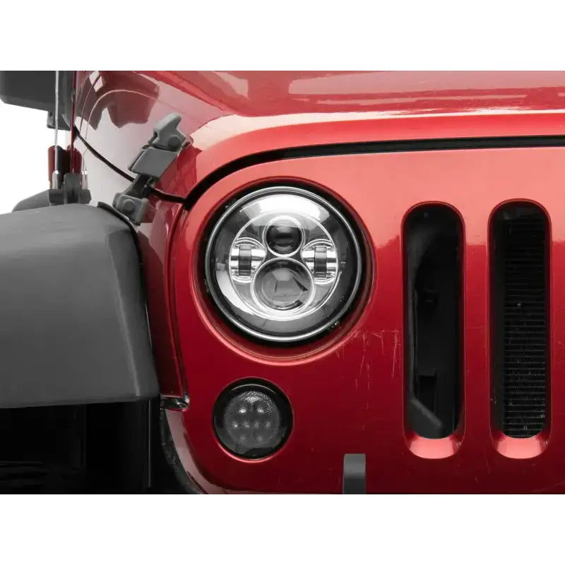 Red Jeep headlight showcasing Raxiom LED Daymaker headlights for Jeep Wrangler TJ/JK