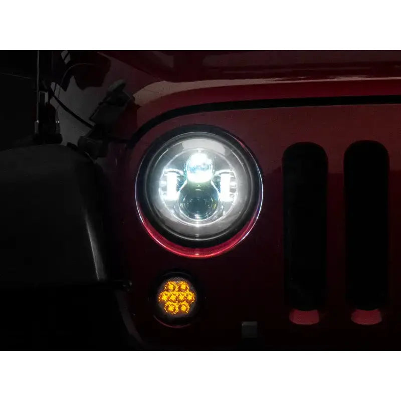 Illuminated Jeep headlight showing LED Daymaker headlights in chrome housing