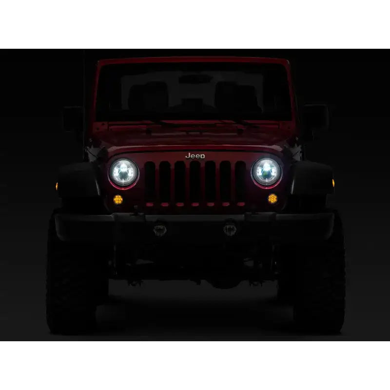 Red Jeep Wrangler with illuminated LED Daymaker headlights in chrome housing