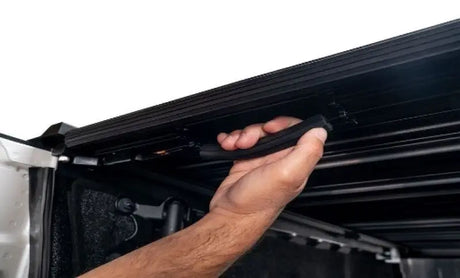 Hand holding black truck bed cover handle for Toyota Tundra CrewMax Retrax IX