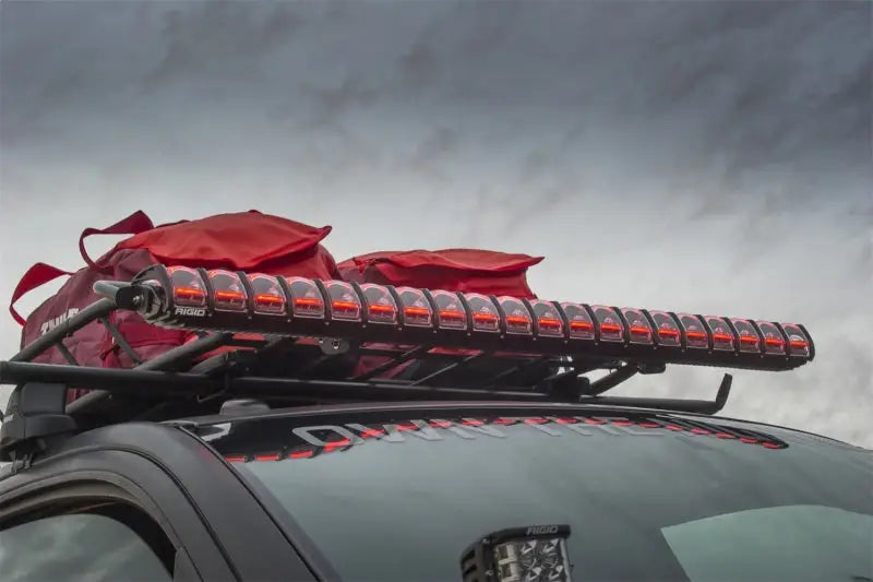 Rigid Industries 30in Adapt Light Bar mounted on vehicle roof, showcasing advanced LED technology and customizable accent lighting against an overcast sky.
