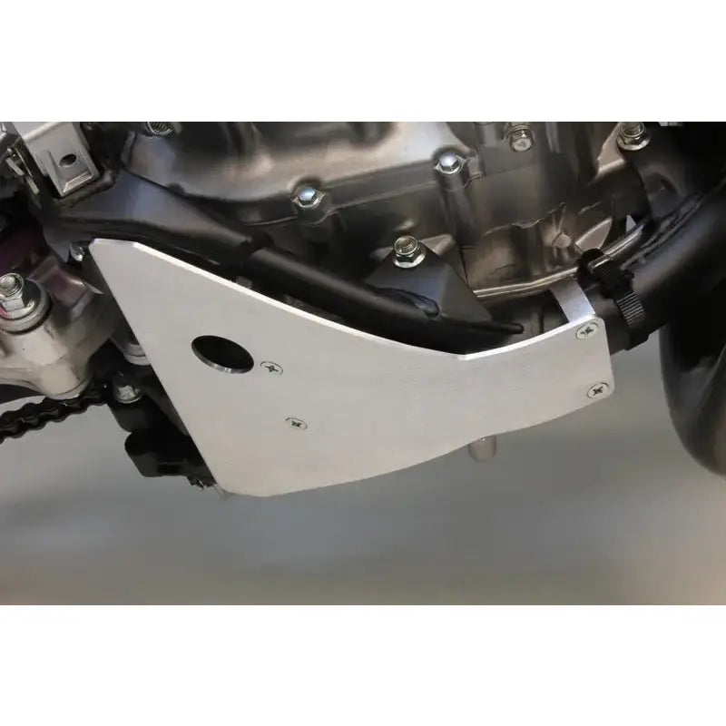 Silver motorcycle skid plate with oil drain access protecting frame rails