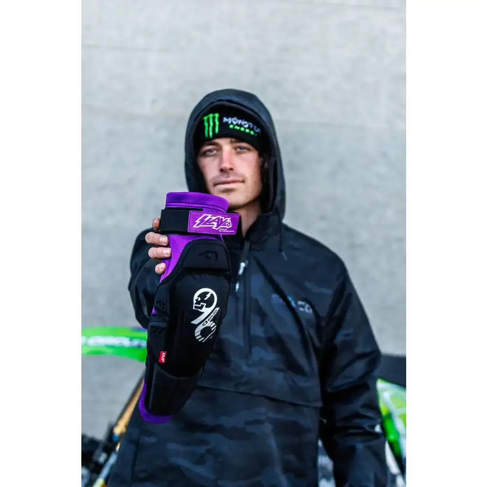 SLAY96K-L/X Slayco96 Knee Pad Lg/Xl being held up by a person wearing a black hooded jacket and a beanie.