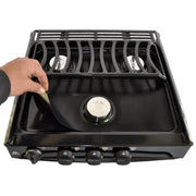 SWRV300 Stove Wrap Stove Top Protectors for Atwood/Dometic stoves, showing a hand lifting the protector to reveal the stove surface underneath.
