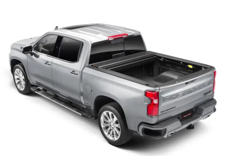 Silver Chevrolet Silverado pickup with a matte black power retractable tonneau cover