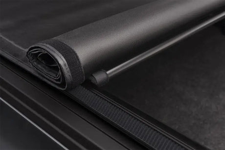 Rolled-up black Truxport bed cover for Ford F-150 6ft 6in truck