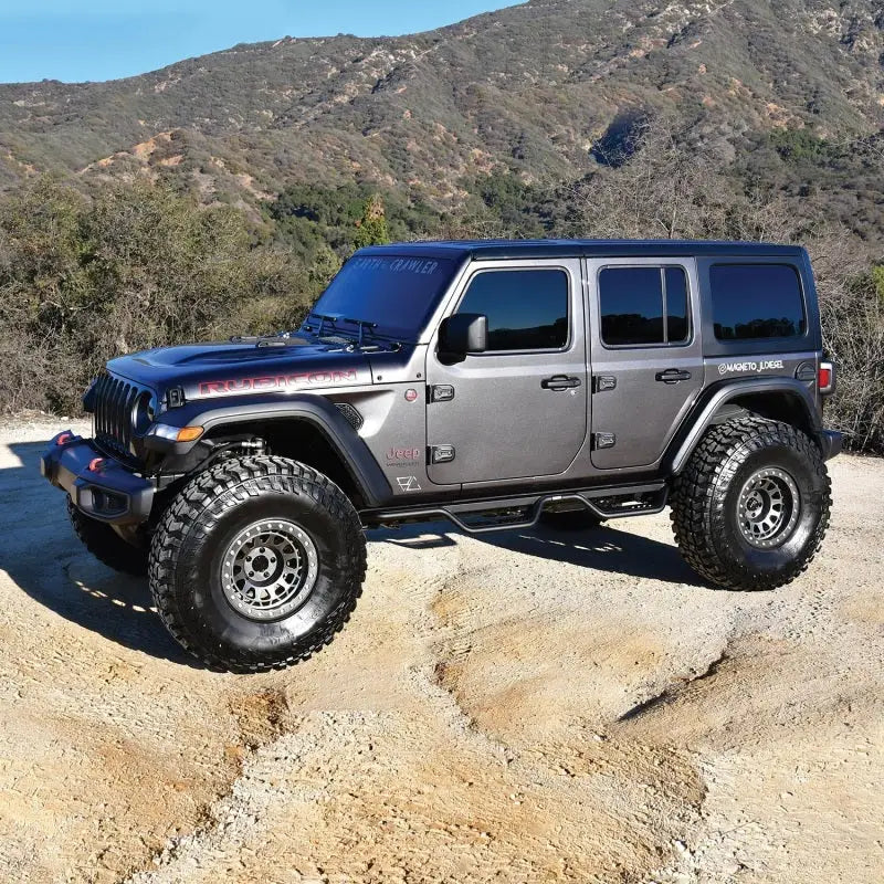Westin 18-22 Jeep Wrangler JL Unlimited Outlaw Nerf Step Bars installed on a rugged Jeep Wrangler, with a mountainous backdrop.