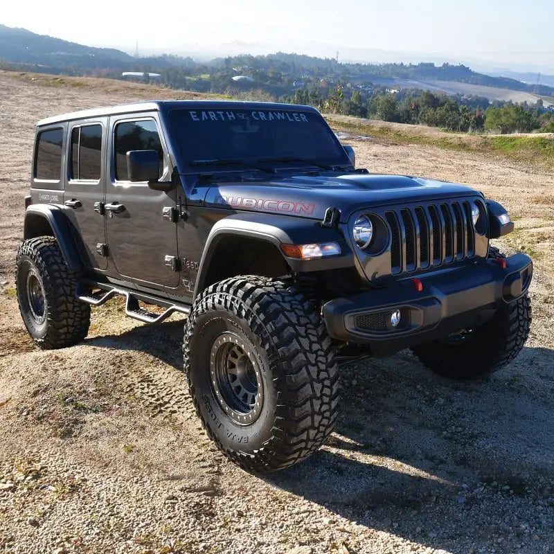 Black 2018-2023 Jeep Wrangler JL Unlimited equipped with Westin Outlaw Nerf Step Bars on an off-road trail.
