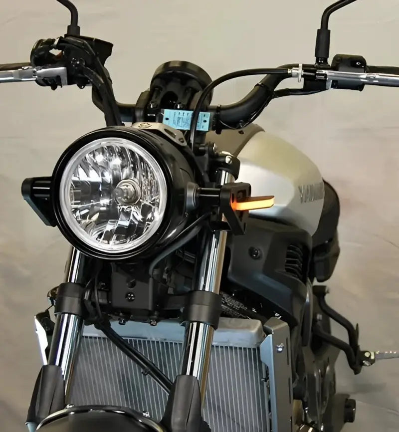 Silver motorcycle with round headlight and black handlebars showcasing LED turn signals